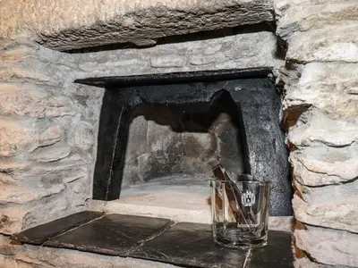 a glass sitting in front of a stone fireplace at Ludgvan Cottage in Gorran Haven