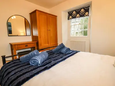 a bedroom with a bed with blue pillows on it at Ludgvan Cottage in Gorran Haven