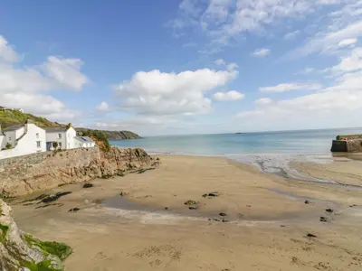 a beach with a white house and the ocean at Ludgvan Cottage in Gorran Haven
