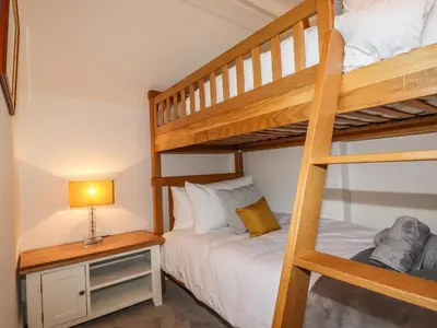 a bedroom with two bunk beds and a lamp at Ludgvan Cottage in Gorran Haven
