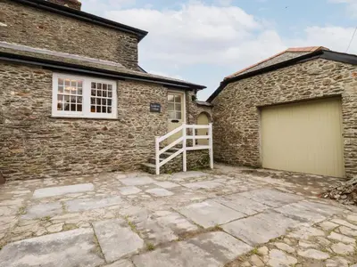 a stone driveway in front of a brick house with a garage at Ludgvan Cottage in Gorran Haven