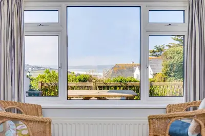 a room with two windows and a table and chairs at Bella Vista in Polzeath