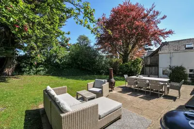 a patio with several chairs and tables and a grass yard at Sandy Lodge Rock in Padstow
