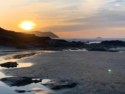 a sunset on a beach with the sun setting at Sandy Lodge Rock in Padstow