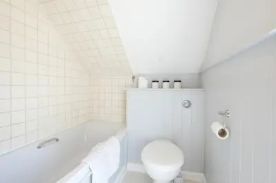 a white bathroom with a toilet and a bath tub at Sandy Lodge Rock in Padstow