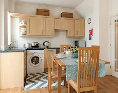 a kitchen with a table and chairs and a kitchen with a dishwasher at St Martins Apartment in Saint Minver