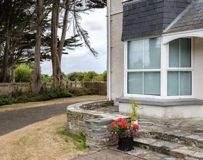 a house with a window and flowers on the steps at St Martins Apartment in Saint Minver