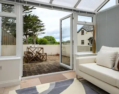 a living room with a couch and a sliding glass door at St Martins Apartment in Saint Minver