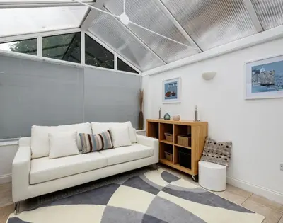 a living room with a white couch and some windows at St Martins Apartment in Saint Minver