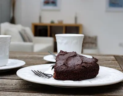 a piece of chocolate cake on a plate on a table at St Martins Apartment in Saint Minver