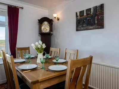 a wooden table with chairs and a grandfather clock at Hillview in Wadebridge