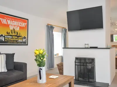 a living room with a fireplace with a tv above it at Orchard Cottage in Saint Endellion
