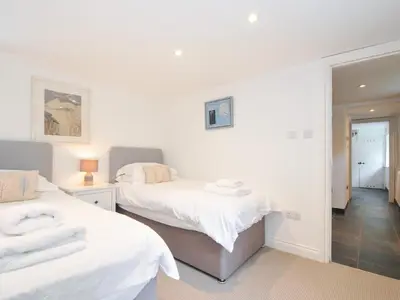 two beds in a room with white walls at Orchard Cottage in Saint Endellion