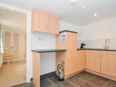 a kitchen with wooden cabinets and a counter top at Orchard Cottage in Saint Endellion