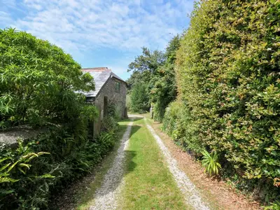 an old house on a dirt road next to trees at Orchard Cottage in Saint Endellion