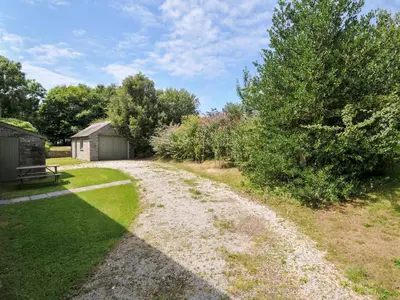 a dirt road in a garden with a tree at Orchard Cottage in Saint Endellion
