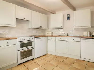 a kitchen with white cabinets and white appliances at Blue Crab Cottage in St Austell