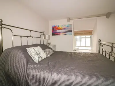 a bedroom with a gray bed with a window at Blue Crab Cottage in St Austell