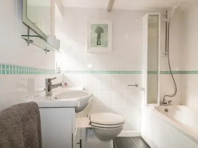 a white bathroom with a toilet and a sink at Blue Crab Cottage in St Austell
