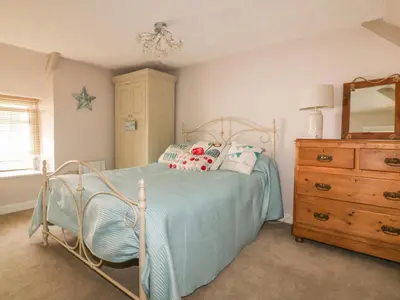a bedroom with a bed and a dresser and a mirror at Blue Crab Cottage in St Austell