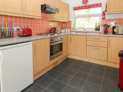 a kitchen with wooden cabinets and a tile floor at Ballasalla in Liskeard