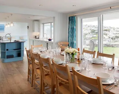 a dining room with a table and a kitchen at The White House in Polzeath