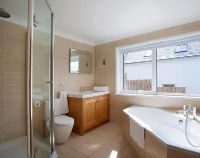 a bathroom with a tub and a toilet and a sink at The White House in Polzeath