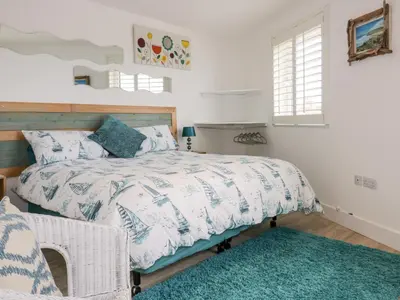 a bedroom with a bed and a blue rug at Fistral Drift in Newquay