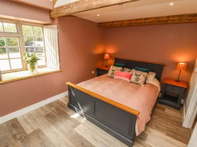 a bedroom with a large bed and two windows at The Roost in Helston