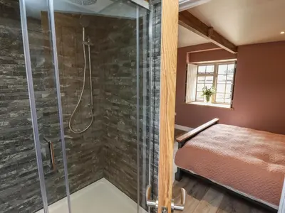 a bathroom with a shower and a bed in a room at The Roost in Helston