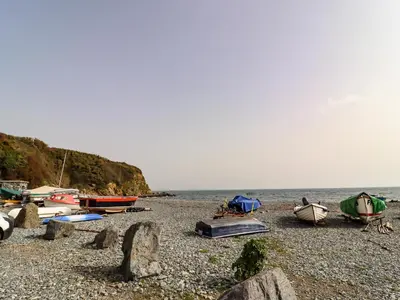 a group of boats sitting on a rocky beach at The Roost in Helston