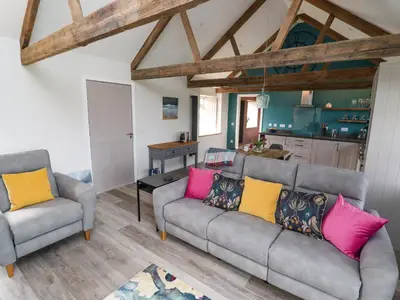a living room with two couches and a kitchen at The Roost in Helston