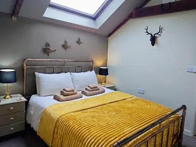 a bedroom with a bed with towels on it at Cosy barn on rural smallholding with alpacas, goats & pigs in Stithians