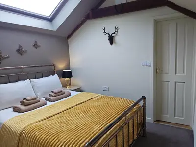 a bedroom with a bed with towels on it at Cosy barn on rural smallholding with alpacas, goats & pigs in Stithians