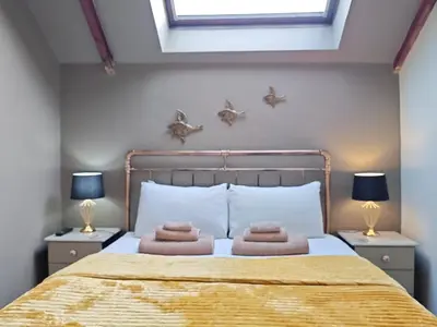 a bedroom with a large bed with two lamps at Cosy barn on rural smallholding with alpacas, goats & pigs in Stithians