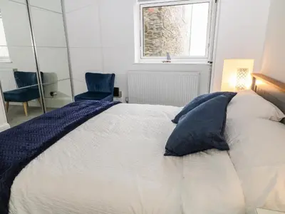 a bedroom with a bed with blue pillows and a window at Harbour Hideaway in Looe