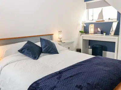 a bedroom with a large bed with blue pillows at Harbour Hideaway in Looe