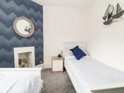 a bedroom with two beds and a mirror at Harbour Hideaway in Looe