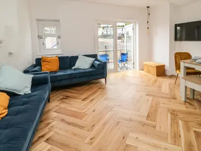 a living room with a blue couch and a wooden floor at Harbour Hideaway in Looe