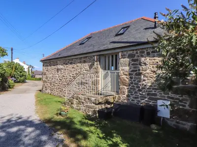 a stone house with a gate on the side of it at The Old Byre in Falmouth