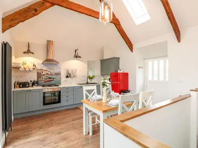 a kitchen with blue cabinets and a table with chairs at The Old Byre in Falmouth