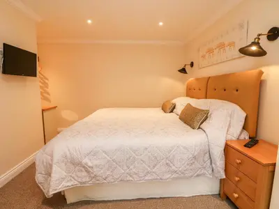 a bedroom with a bed and a dresser and a television at The Old Byre in Falmouth