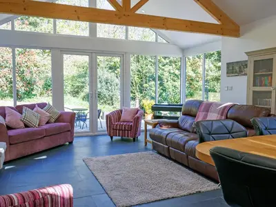 a living room with couches and a table and windows at The Old Vicarage Retreat in Bodmin