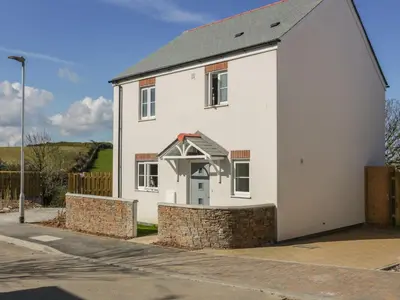 a white house with a stone wall at 4 Trerammet Crescent in Tintagel