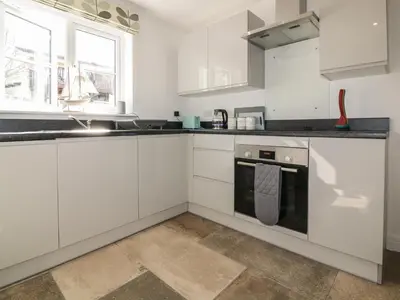 a white kitchen with white cabinets and a stove at 4 Trerammet Crescent in Tintagel