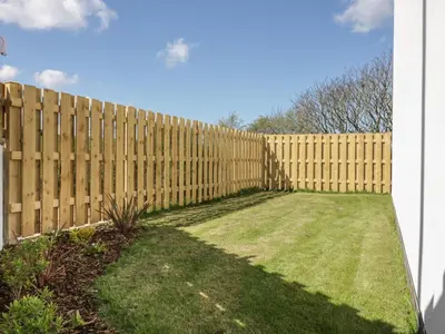 a wooden fence in a yard with grass at 4 Trerammet Crescent in Tintagel