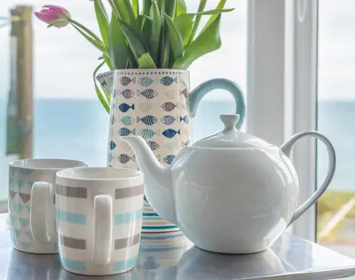 a table with a tea pot and a vase and cups at The View in Port Isaac