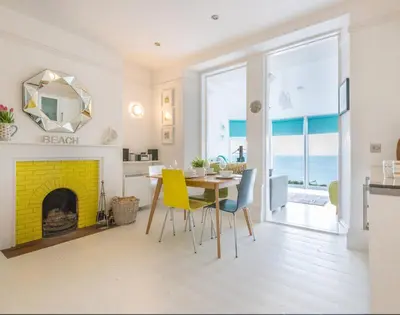 a living room with a table and a yellow fireplace at The View in Port Isaac