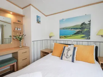 a bedroom with a bed and a desk and a mirror at Orchard View in Tintagel