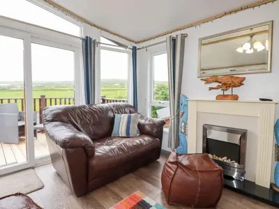 a living room with a leather couch and a fireplace at Orchard View in Tintagel